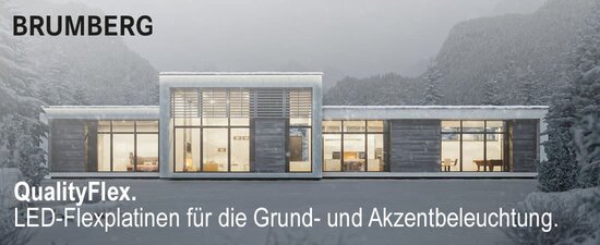 Von innen beleuchtetes Haus im Schnee mit kompletter Fensterfront