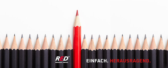 Mehrere schwarze Stifte und ein roter Stift welcher höher herausragt.