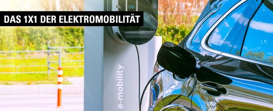 Elektroauto während des Ladevorgangs mit angeschlossenem Ladekabel an Ladesäule im Freien.