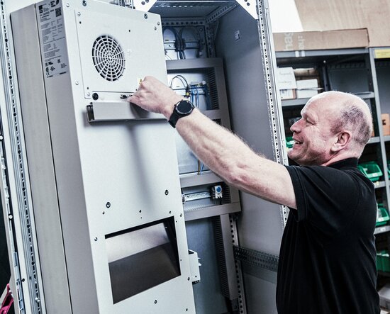 Ein Mitarbeiter arbeitet an einem Schaltschrank in der Werkstatt.