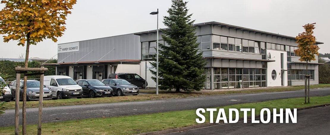 Außenansicht der HARDY SCHMITZ Filiale in Stadtlohn mit Parkplatz und herbstlichen Bäumen